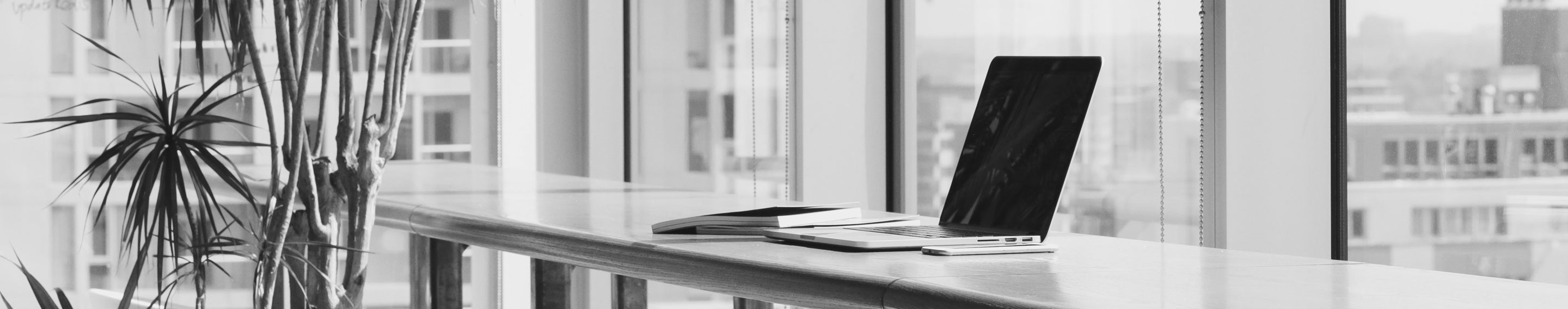 laptop on desk in open office next to window